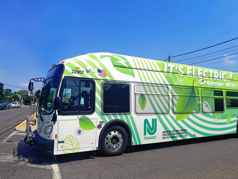 A white NJ Transit electric bus with green leaf designs
